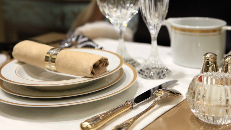 A table setting of fine china and crystal with beige linens
