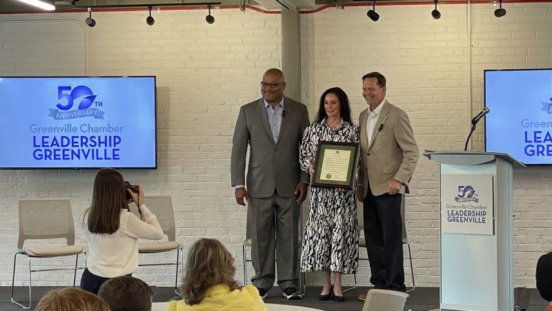 Greenville Chamber President and CEO Carlos Phillips, left, and Director of talent, education and leadership Cheryl Garrison, center, accept a proclamation from Greenville City Councilman John DeWorken declaring April 3. 2024, as Leadership Greenville Day in recognition of the program's 50th anniversary
